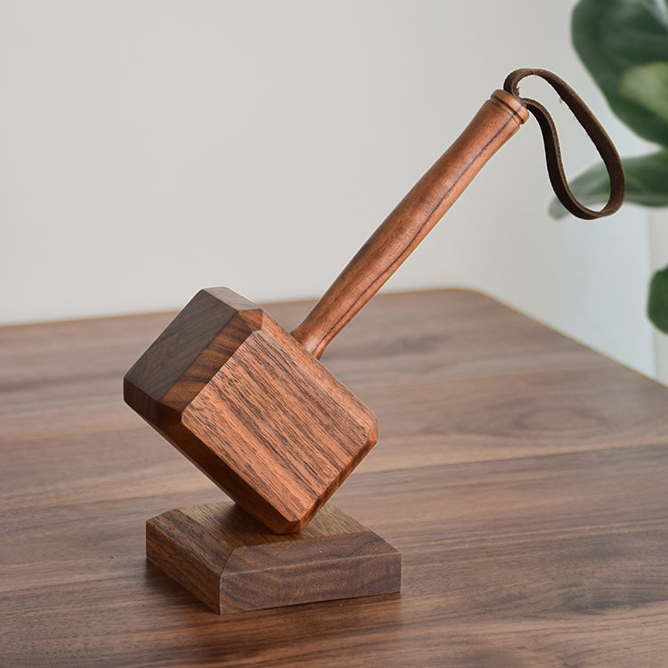 Hammer-shape wooden bottle opener with leather strap angled on side table beside rounded wooden tissue box