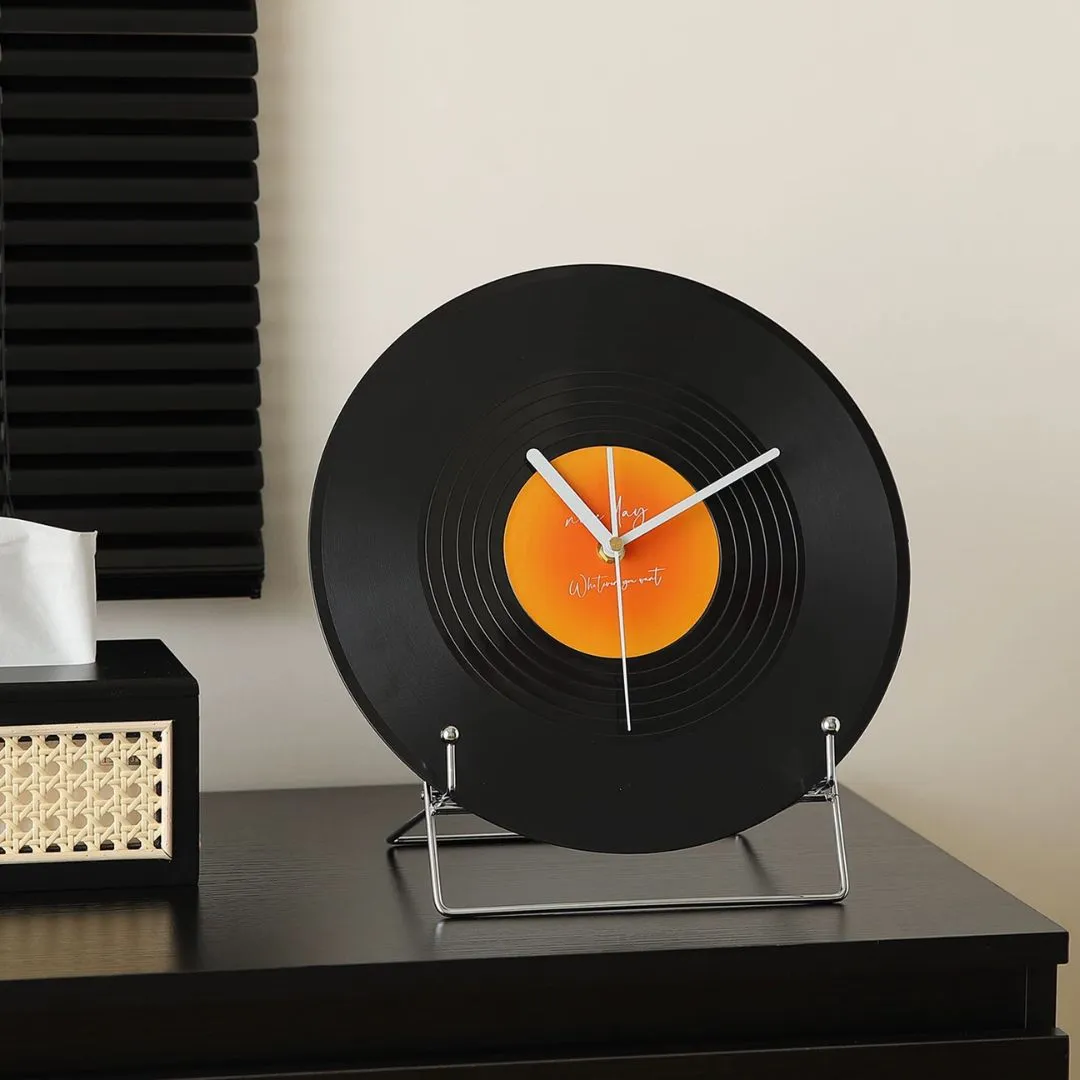 Black vinyl-record desktop clock on dark wood cabinet beside cane-front tissue box