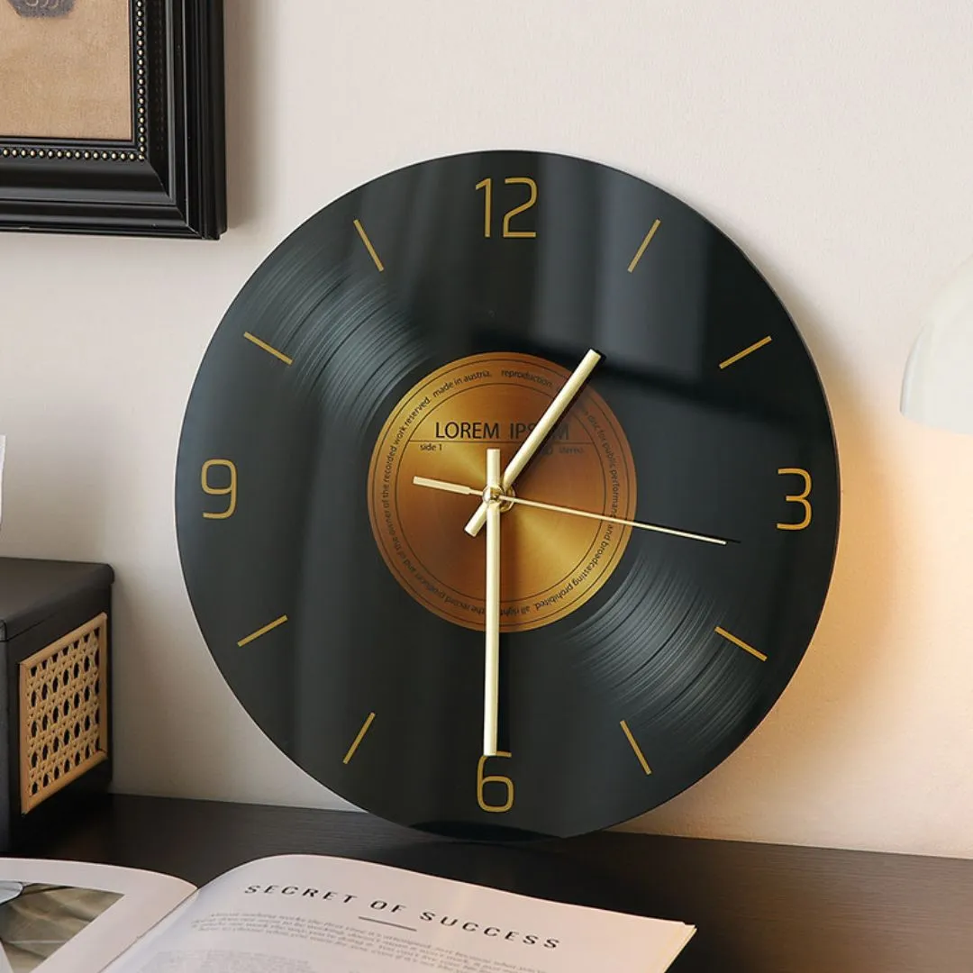 Vinyl-record desk clock with gold numerals on dark wood beside small pleated cream lamp