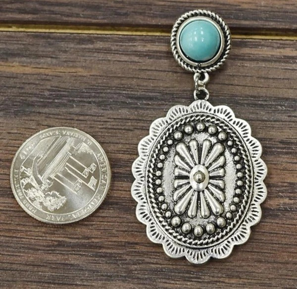 Detailed view of geometric concho cross earrings with turquoise-colored accents