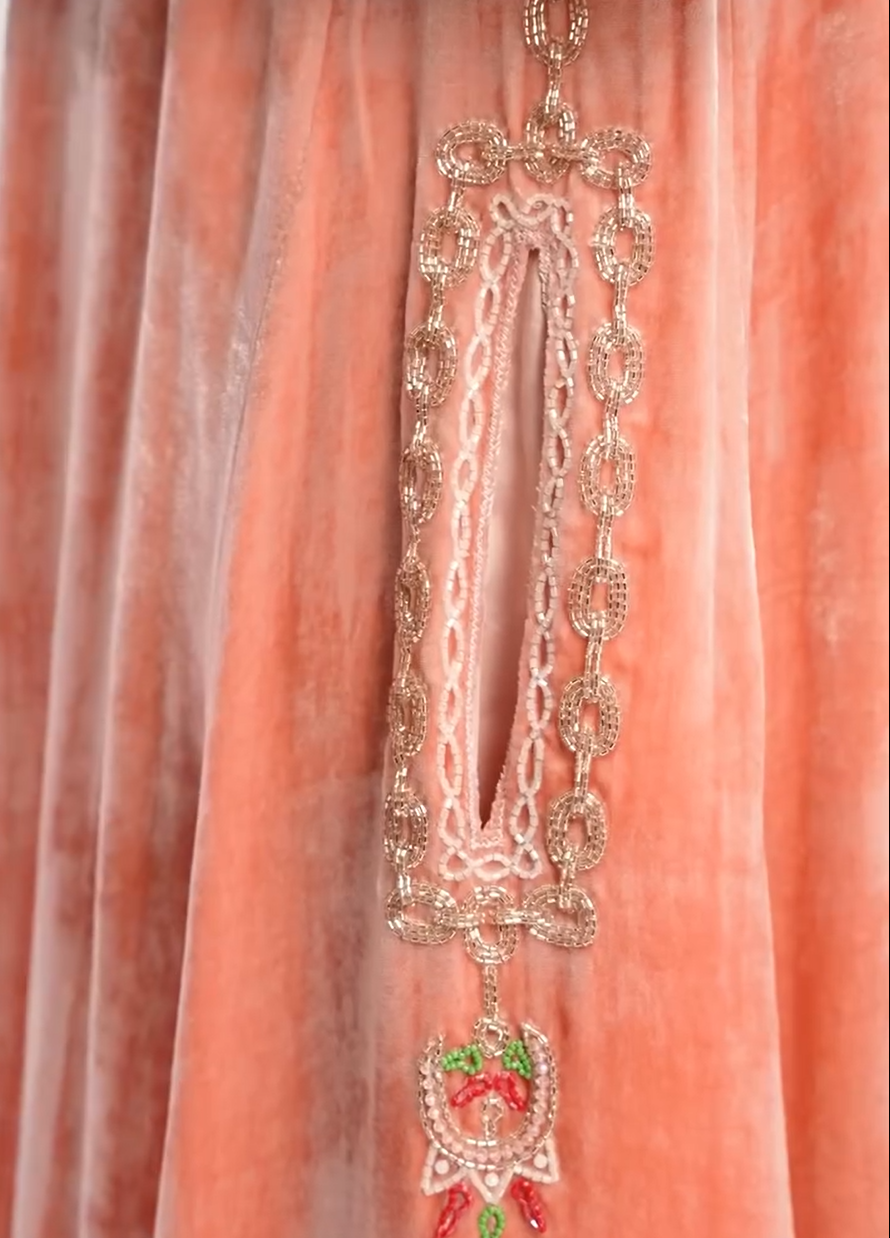 A luxurious velvet dress in light pink, decorated with embroidery.