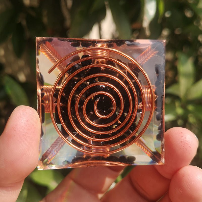 Obsidian orgonite pyramid on a neutral background, highlighting its protective symbol - KARMAKIND