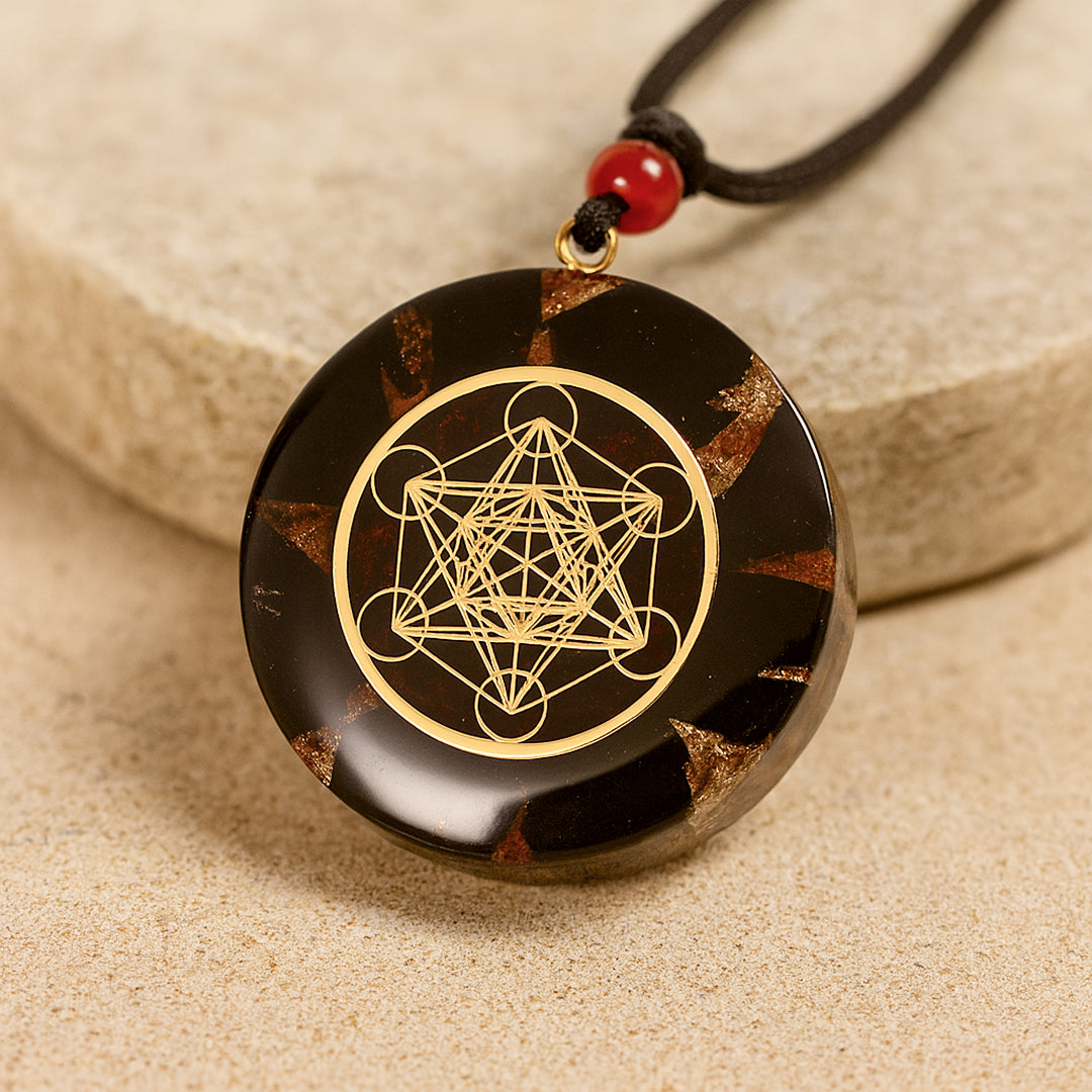 Metatron's Cube Orgonite Pendant in Obsidian and Garnet with golden geometric patterns on a dark bac