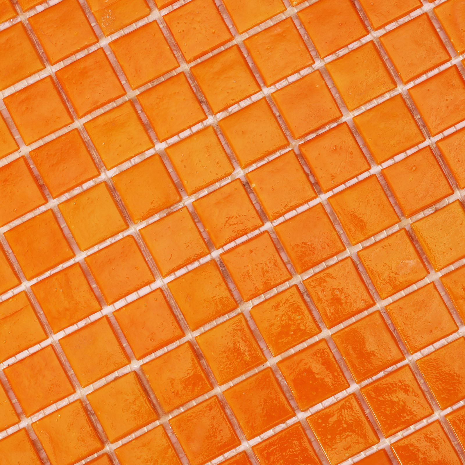 Close-up view of matte orange glass mosaic tiles with intricate detailing.
