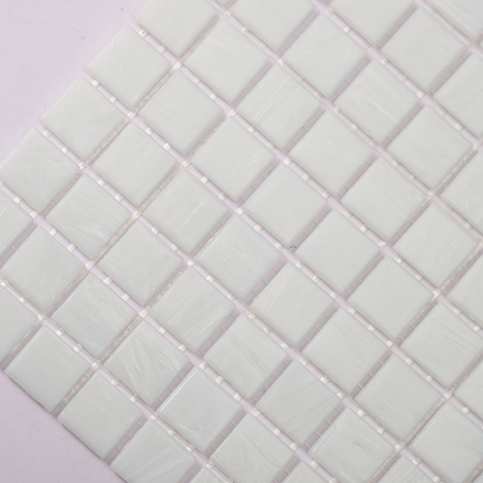 Close-up view of matte white glass mosaic tiles with subtle texture.

