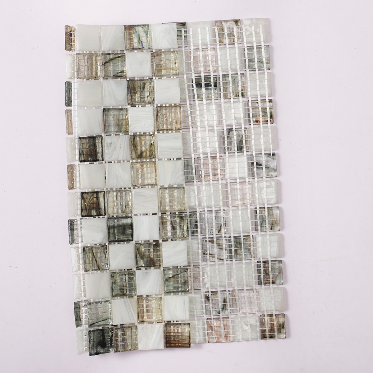 A sheet of amber translucence white and gray glass mosaic tile with a folded back.
